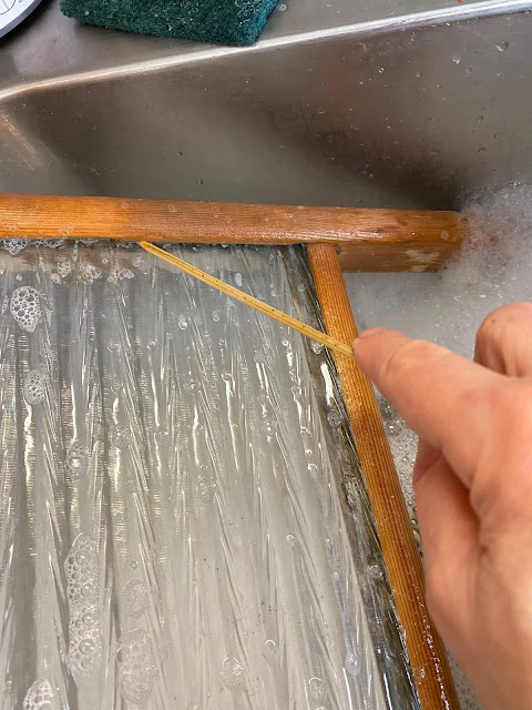 Photo of a vintage washboard being cleaned in the kitchen sink.