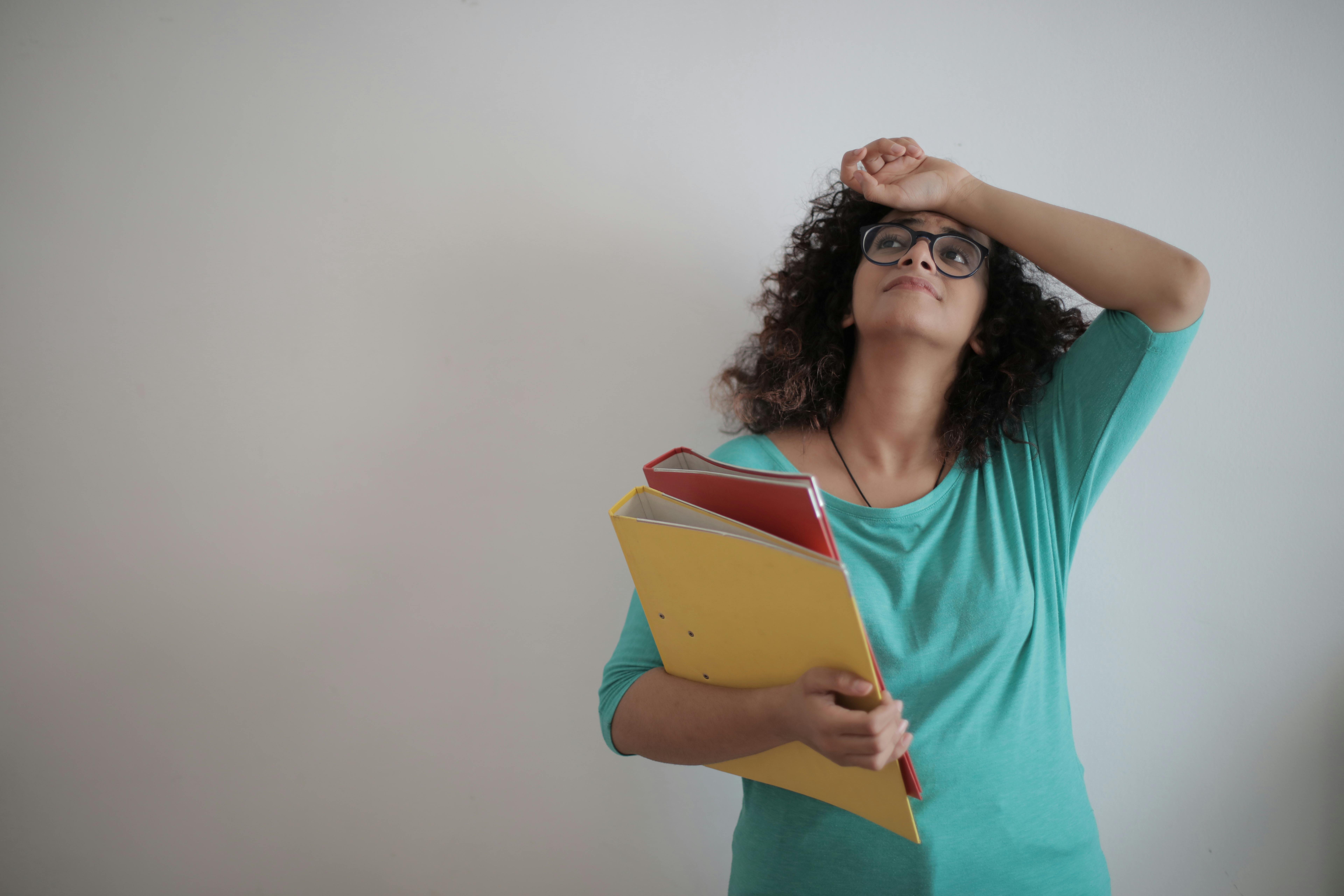 A frustrated and drained woman holding folders | Source: Pexels