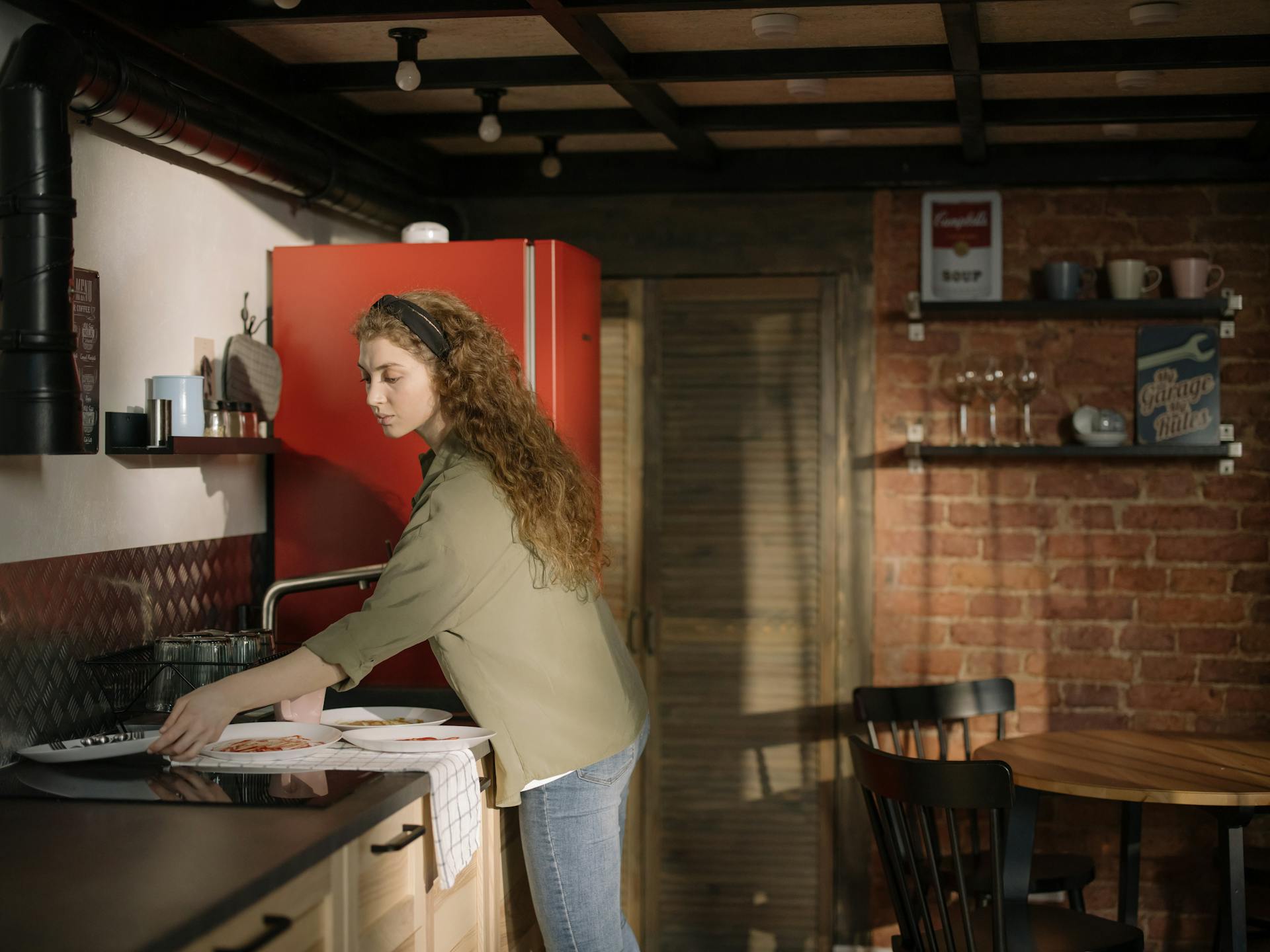 A young woman clearing plates in the kitchen | Source: Pexels